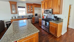 Una cocina con encimeras de granito, armarios de madera y electrodomésticos de acero inoxidable, además de una isla grande.