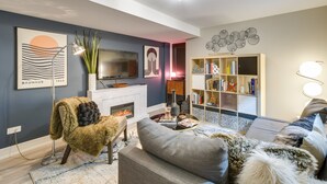 Un salon moderne avec une cheminée, un canapé, une bibliothèque et un téléviseur à écran plat.