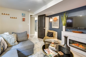 Relax in this stylish living room with a grey sofa, flat-screen TV, and cozy fireplace.