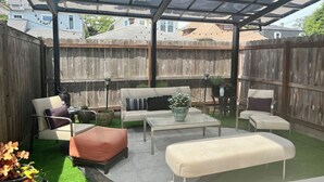 Une terrasse couverte, agrémentée d’une clôture en bois, de mobilier d’extérieur et d’une table en verre.
