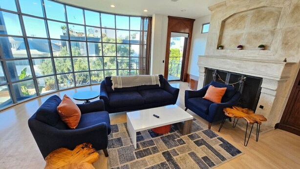 A modern living room with a fireplace, large windows, and a view of the outdoors.