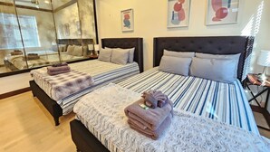 A hotel room with two beds, a large mirror, and artwork on the walls.