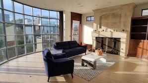 A spacious living room with a fireplace, large windows, and modern furniture.