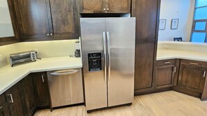 A kitchen with dark wooden cabinets, a stainless steel refrigerator, a built-in oven, and a white countertop.