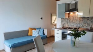 Un espacio habitable compacto con sofá, mesa de comedor y kitchenette.