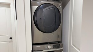 Une petite buanderie équipée de deux machines à laver à chargement frontal superposées.