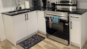 Une cuisine moderne avec des meubles blancs, une cuisinière en acier inoxydable, un four à micro-ondes et un évier.