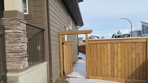 Une propriété résidentielle dotée d’une entrée revêtue de pierres, d’un portail en bois et d’une allée recouverte de neige.