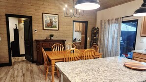 A wooden interior with a dining area, kitchen, and a large window. - BRAND NEW CUSTOM BUILT HOME WITH AC! FENCED FOR YOUR PUPS! (Pinetop-Lakeside)