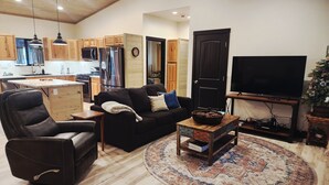 A modern living room with a leather chair, a black sofa, a coffee table, and a TV. - BRAND NEW CUSTOM BUILT HOME WITH AC! FENCED FOR YOUR PUPS! (Pinetop-Lakeside)