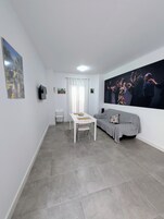 Een moderne woonkamer met een eettafel, een bank en een groot schilderij aan de muur.