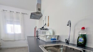Une cuisine équipée d’un évier en acier inoxydable, d’un égouttoir, d’un four à micro-ondes et d’une bouteille de liquide vaisselle.