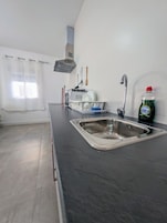 Een keuken met een roestvrijstalen spoelbak, een afwassysteem, een magnetron en een fles afwasmiddel.