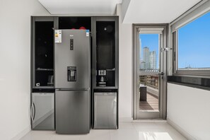 Une cuisine moderne équipée d’un grand réfrigérateur, d’une machine à café et d’un four encastré.