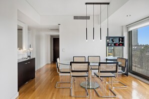 Un comedor moderno con una mesa de vidrio, sillas de mimbre y un mueble de madera oscura.