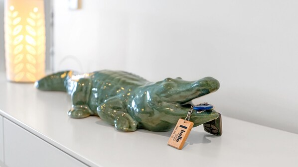 A ceramic crocodile figurine with a tag on a white surface.