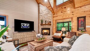 Una sala de estar acogedora con chimenea de piedra, techo de madera y asientos cómodos.