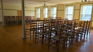 A spacious room with rows of wooden chairs and tables, large windows, and a high ceiling. - Enfield Shaker Museum (Enfield)