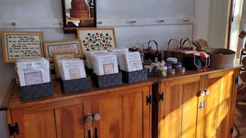 A wooden cabinet with drawers, a mirror, and various items including framed quotes and a cross-stitch kit.