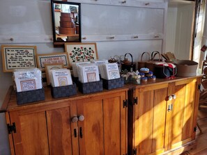 A wooden cabinet with drawers, a mirror, and various items including framed quotes and a cross-stitch kit.