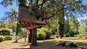 A treehouse structure built into a large tree, surrounded by a well-maintained garden with various plants and a stone wall. - Villa Rocks 3120 - A haven of peace at the foot of Roquebrune rock (Roquebrune-sur-Argens)