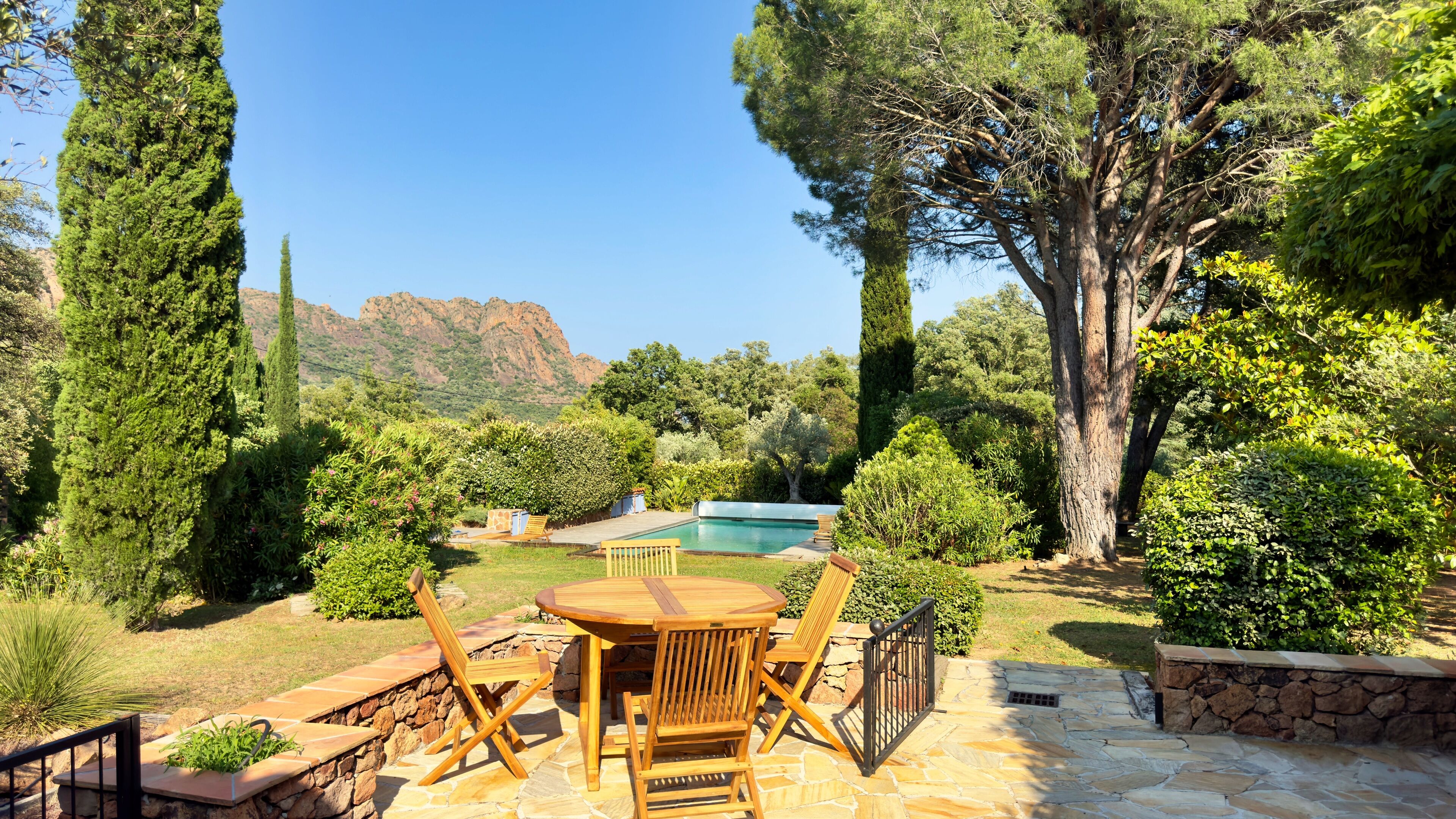Eine Terrasse mit Pool, umgeben von Steinmauern und verschiedenen Pflanzen.