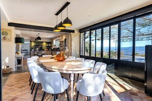 Un comedor moderno con una mesa redonda, sillas blancas e iluminación colgante.