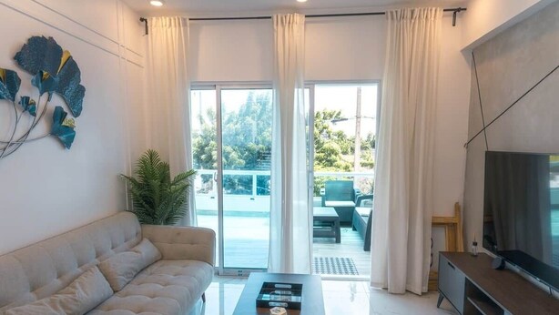 A modern living room with a sofa, coffee table, and TV. - Tropico Smart by Suarez Properties | 2BR & Jacuzzi (Santo Domingo Este)