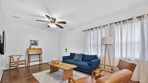 A living room with a blue sofa, wooden coffee table, leather armchair, and a ceiling fan.