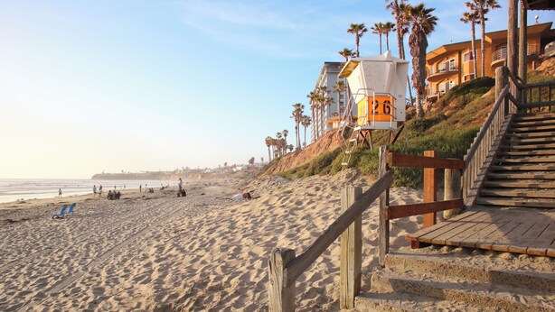 A beach with wooden stairs leading to a building with a lifeguard tower. - Bright 3-bedroom townhouse, w/ocean views roof deck, AC, walk to everything! (San Diego)