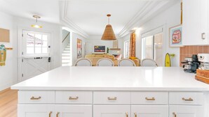 A spacious kitchen with a large island, white cabinetry, and a hanging light fixture. - Bright 3-bedroom townhouse, w/ocean views roof deck, AC, walk to everything! (San Diego)
