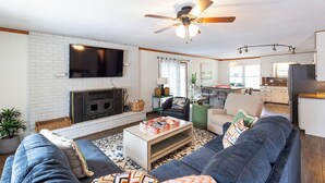 A modern living room with a fireplace, sofa, coffee table, and a TV mounted on the wall. - Lakefront Home on Grand Lake in Grove – Dock, 10 Beds, Game Room, Honey Creek (Grove)