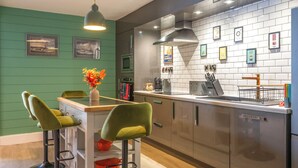 Une cuisine moderne avec des murs verts, un coin bar et une machine à café.