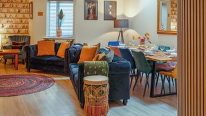 Un salon comprenant un canapé, des fauteuils, une table à manger et un tapis à motifs.