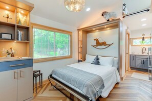 Un dormitorio con cama, mesita de noche y ventana con persianas.