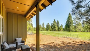 Alpendre coberto com móveis de vime e vista para um campo de golfe.