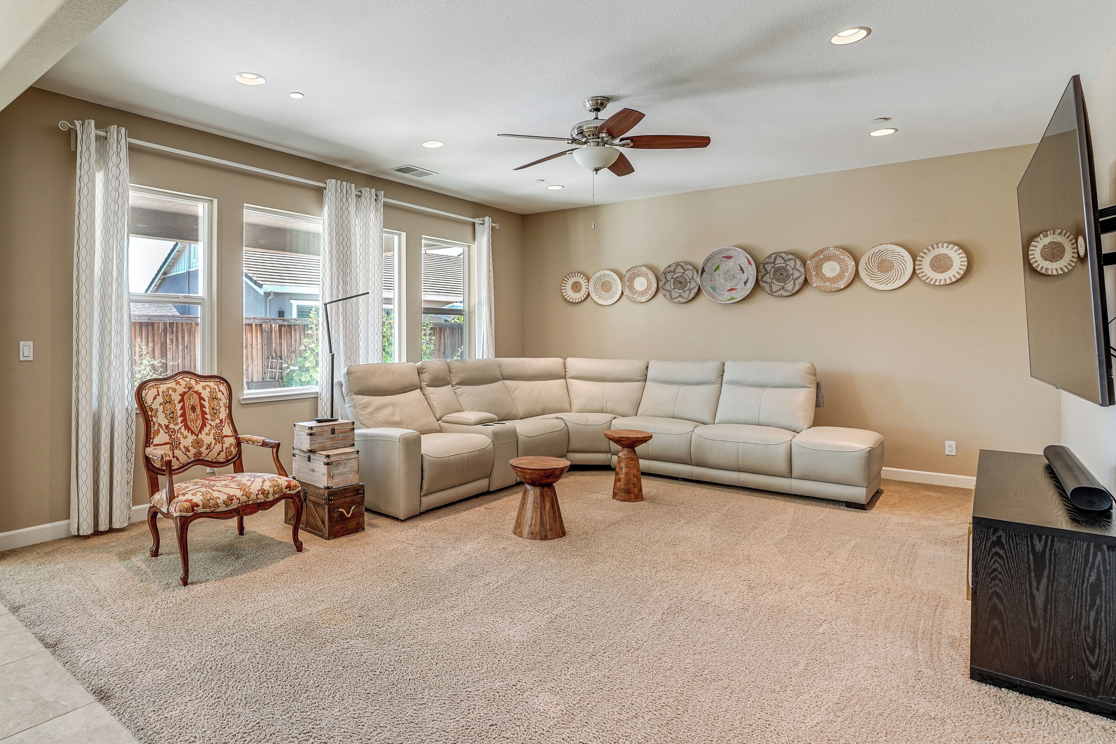 A living room with a beige sofa, a wooden chair, a coffee table, and a ceiling fan.