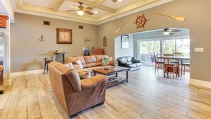 A spacious living room with a brown leather sofa, wooden coffee table, and ceiling fans. - Fish, Swim & More: Lakefront Retreat in Ocklawaha! (Ocklawaha)