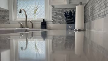 A modern kitchen with a large window, a stainless steel sink, and a brick backsplash.