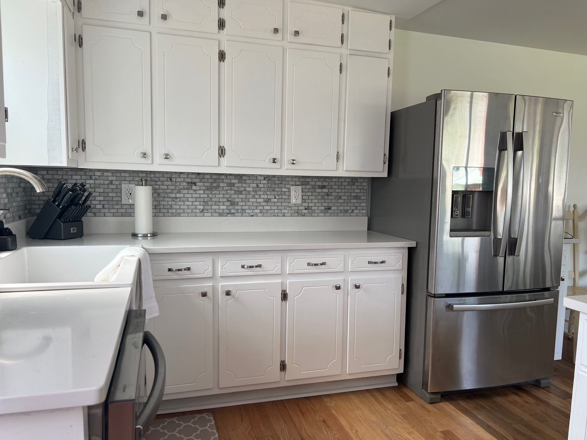 A modern kitchen with white cabinetry, a stainless steel refrigerator, and a built-in sink.