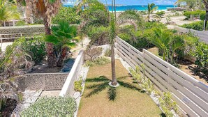 A coastal road with palm trees and a beach in the background. - Villa Côté Sable, Accès plage, Vue mer, Elégance (Orient Bay)