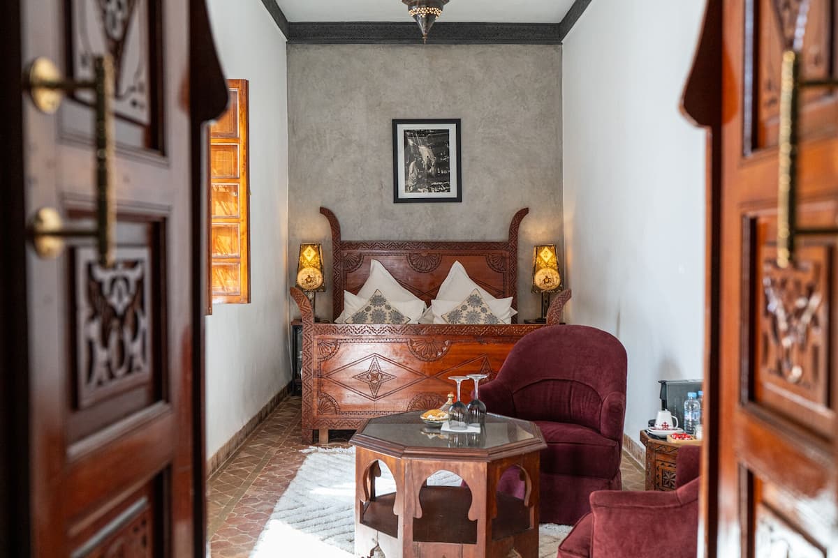 A cozy room with a wooden bed, a red armchair, and a small table.