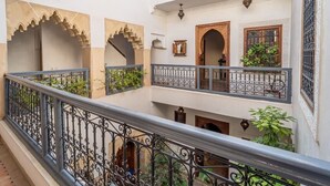 Un patio de varios niveles con arcos ornamentales, balcones y barandillas de hierro forjado.