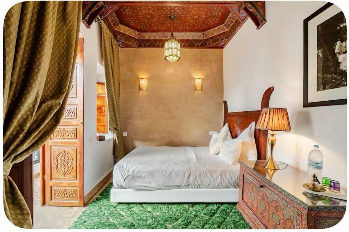 A room with a bed, a nightstand, a lamp, and a wall-mounted light fixture.