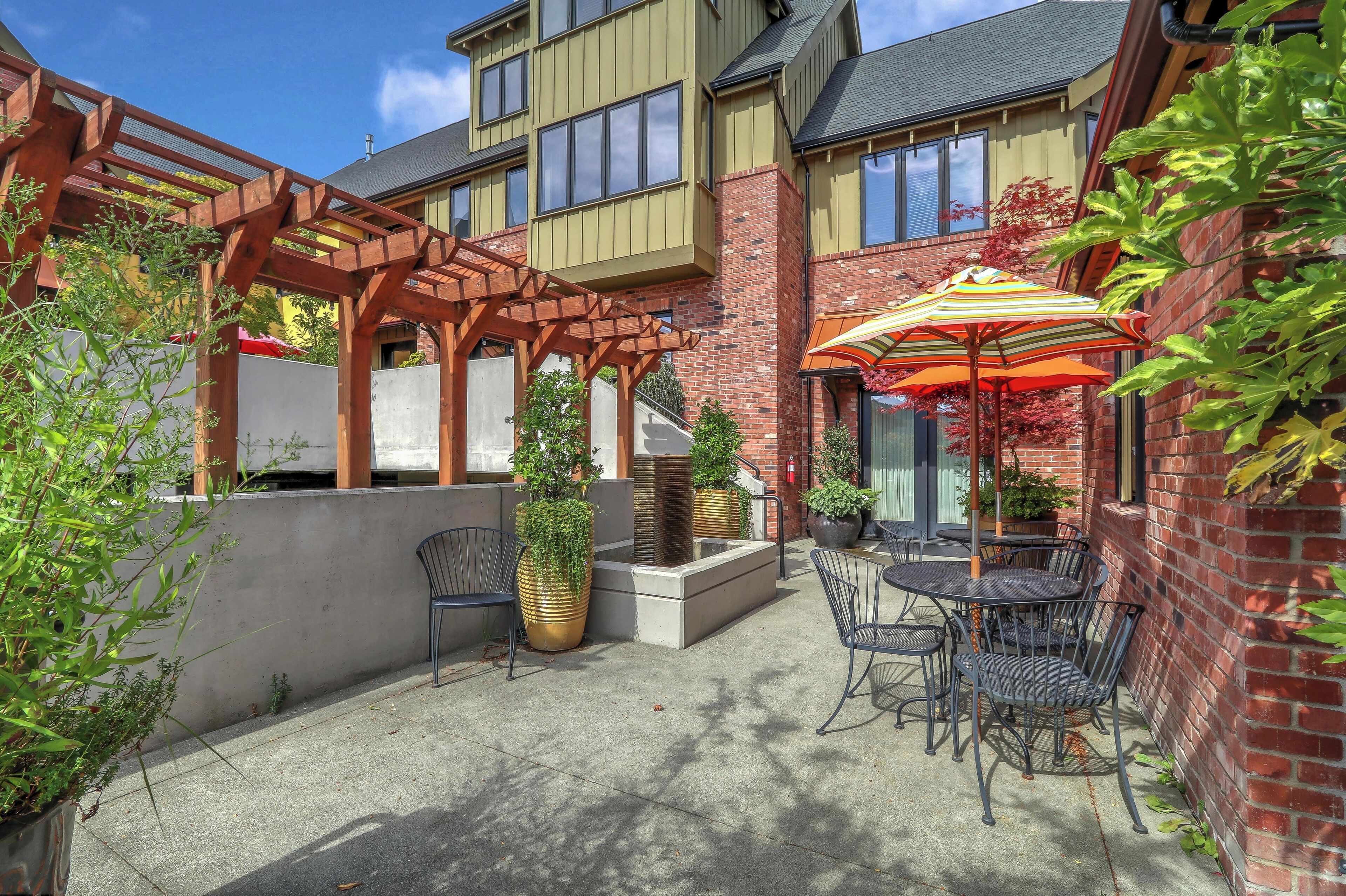 A patio area with outdoor seating, a pergola, and potted plants.