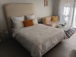 Une chambre d’hôtel avec un grand lit, un canapé, une table basse en verre et une vue sur l’extérieur.
