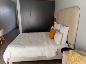 A bedroom with a bed, a wardrobe, and a chair.