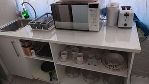 A compact kitchen with a microwave, toaster, and sink. - Close Curtains Maboneng (Johannesburg)