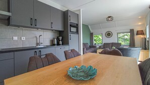 Une cuisine moderne avec des meubles gris, une table à manger en bois et un bol décoratif vert.