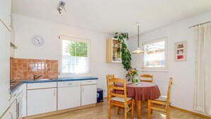 A kitchen with white cabinets, a blue countertop, and a wooden dining table with chairs.